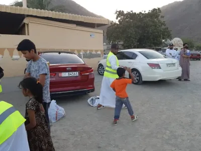 Volunteers in high-visibility vests handing out bags in a mountain village