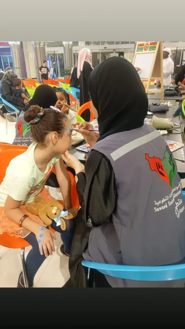 متطوعة تساعد الأطفال على طاولة نشاط